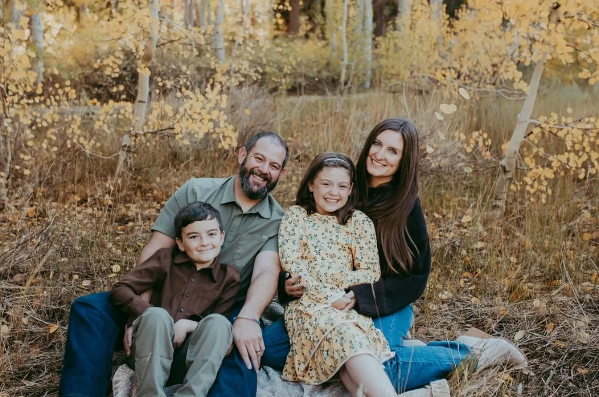 Family of four smiling in autumn forest